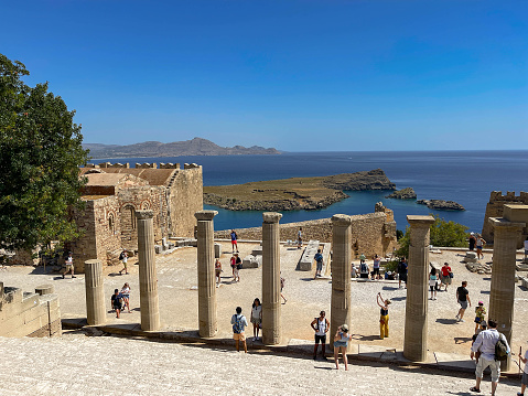 Lindos, Rhodes, Greece - May 2022: Tourists walking around the Acropolis in the town of Lindos