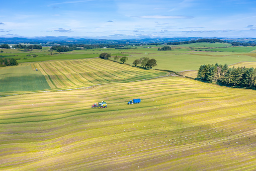 Drone view of tractors working in a field harvesting silage in rural Dumfries and Galloway Scotland