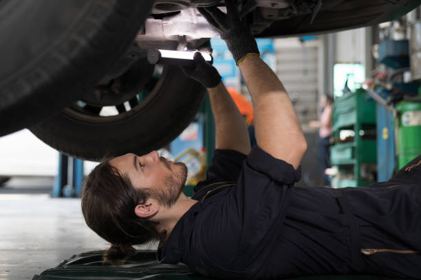 istock Mechanic maintenance underneath lifted car. Technician vehicle service checking under car at automotive motor garage 1412506803