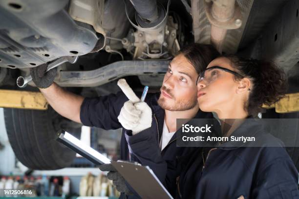 Team Technician Worker Checking Maintenance Car Engine Underneath Lifted Car Group Of Mechanic Vehicle Using Wrench Tool For Maintenance Car At Automative Motor Garage Stock Photo - Download Image Now