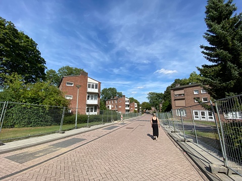 Brunssum, Netherlands - July 09, 2022.  Empty street and one walking  woman with Old apartment buildings being prepared to be demolished.