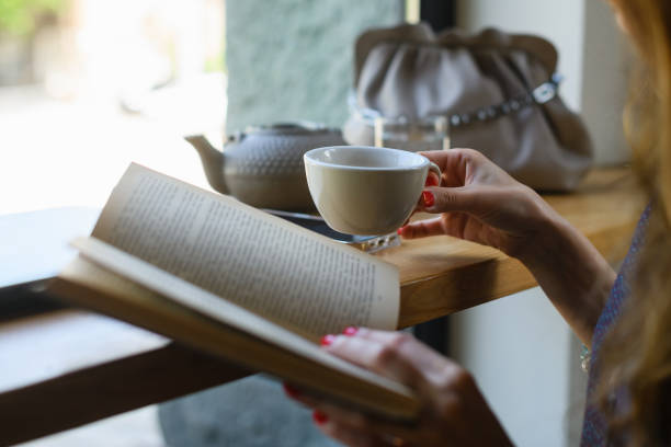 istock Girl reading a book while having breakfast in a coffee shop 1412509642