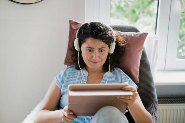 istock woman looking at a tablet with headphones 1412514420