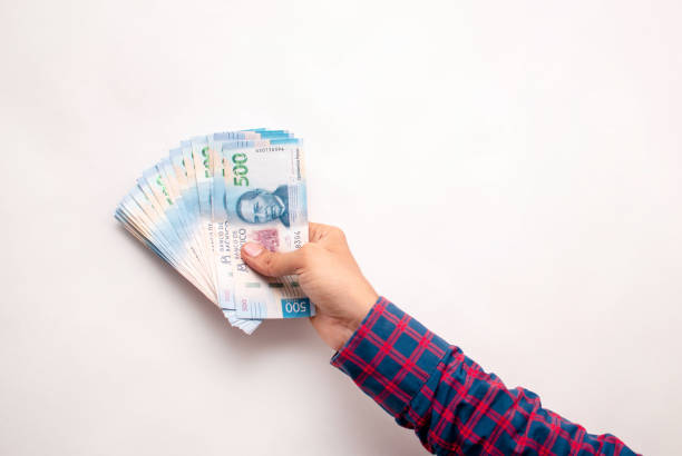 la mano de un hombre sosteniendo varios billetes mexicanos sobre un fondo blanco - mexican currency fotografías e imágenes de stock