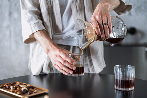 man pour fresh coffee from chemex in glass at kitchen room