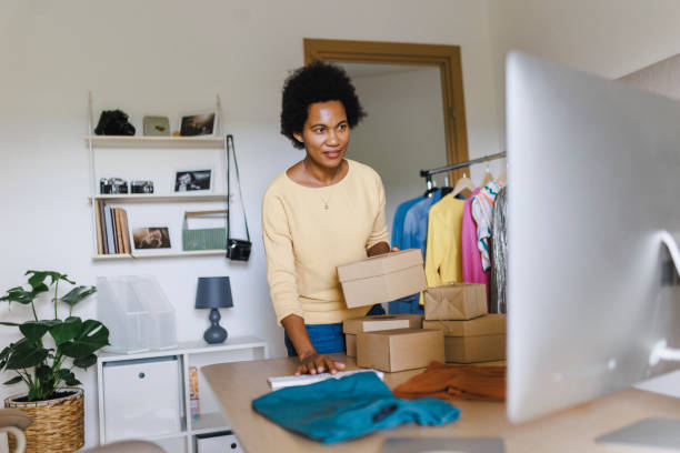 istock African Businesswoman using computer while packing clothes in a cardboard box 1412517058