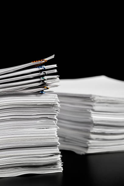 istock Stacks of papers with multicolored paper clips on a dark background 1412518685