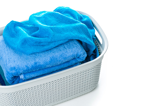 High angle view of blue towels in a laundry basket isolated on white background. High resolution 42Mp studio digital capture taken with Sony A7rII and Sony FE 90mm f2.8 macro G OSS lens
