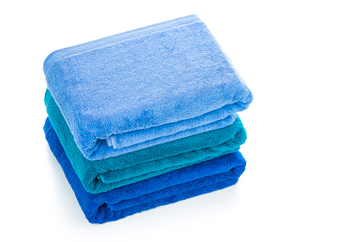 High angle view of a stack of three new blue towels isolated on white background. High resolution 42Mp studio digital capture taken with Sony A7rII and Sony FE 90mm f2.8 macro G OSS lens