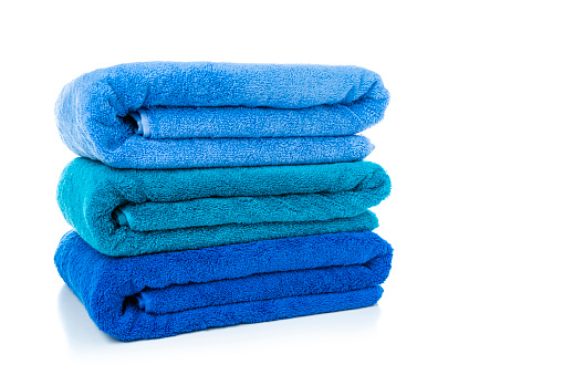 Close up view of a stack of three new blue towels isolated on white background. High resolution 42Mp studio digital capture taken with Sony A7rII and Sony FE 90mm f2.8 macro G OSS lens