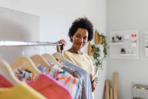 istock Afro Businesswoman using digital tablet while packing clothes in a cardboard box 1412519897