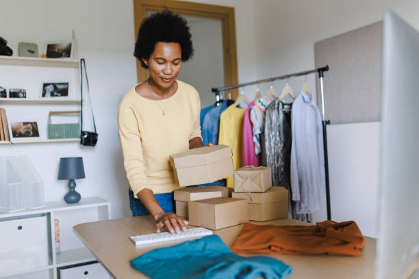 istock African Businesswoman using computer while packing clothes in a cardboard box 1412520853