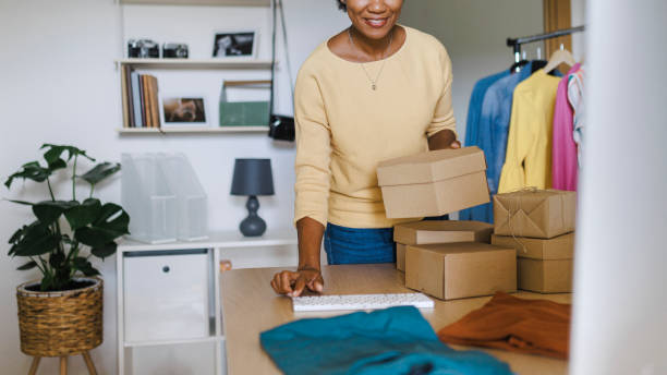 istock African Businesswoman using computer while packing clothes in a cardboard box 1412520873