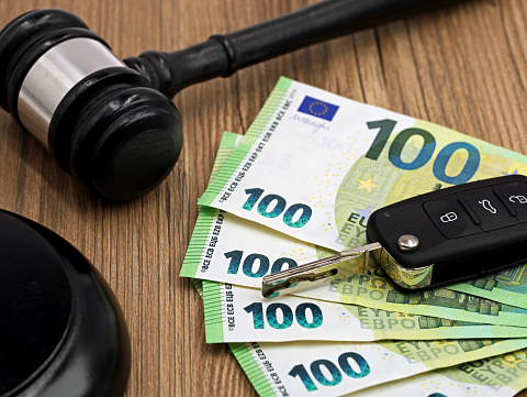 jugde gavel or auction hammer with euro money banknotes and car keys on wooden table.