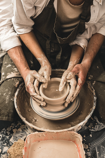 Couple sculpting a clay pot together