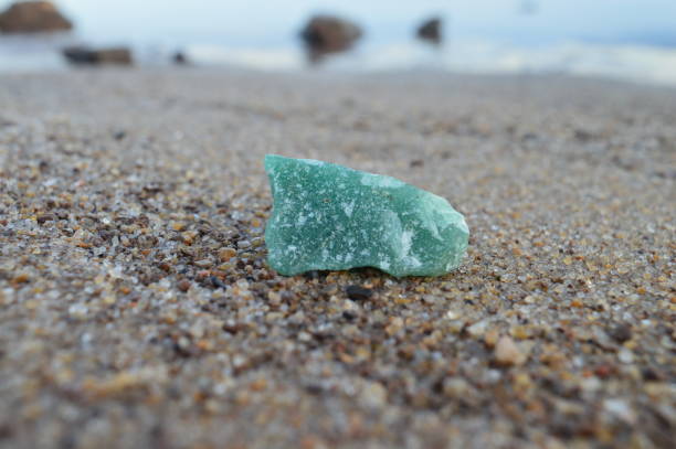 istock Green quartz mineral on sand background 1412524857