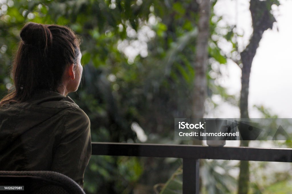 Woman Drinking Coffee and Enjoying the View in the Rainforest of Arenal, Costa Rica Deck Stock Photo