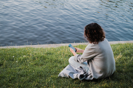 Woman looking at her phone sitting in the park