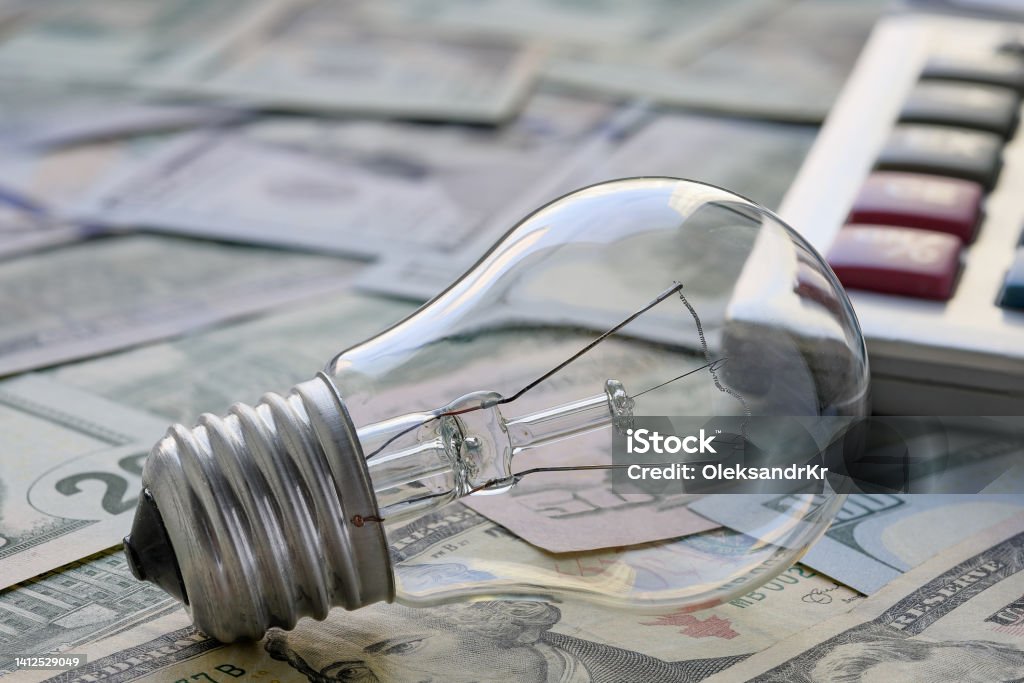 Incandescent lamp on the background of banknotes. The concept of the need to save energy. Selective focus. Backgrounds Stock Photo