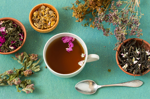 Herbal tea with flower petals and dried herbs in bunches and bowls. Dried and fermented plants for delicious drinks, herbal medicine and health promotion