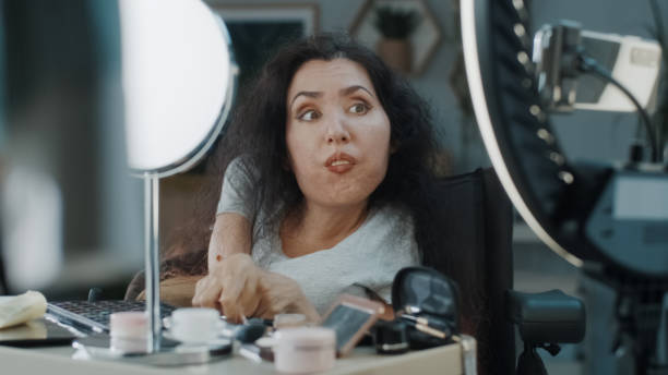 woman with a disability recording makeup tutorial - motorized wheelchair audio imagens e fotografias de stock