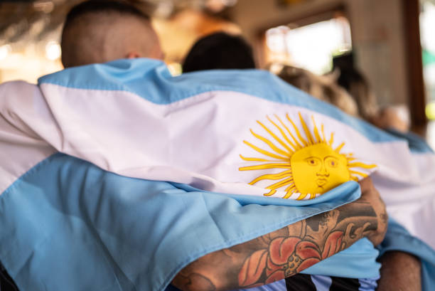 vista trasera de hombres adultos medio abrazados con bandera argentina en un bar - argentina mundial fotografías e imágenes de stock