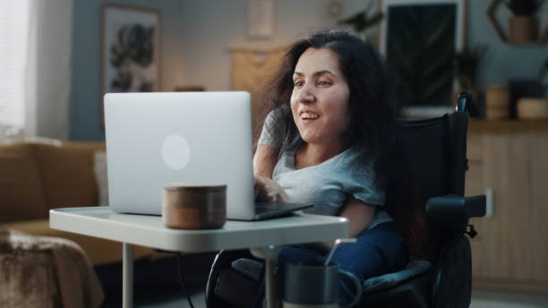 Woman with a disability editing video on laptop stock photo