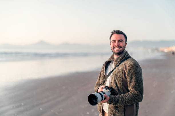 latin photographer holding professional camera on the beach and smiling portrait - nature photographer imagens e fotografias de stock