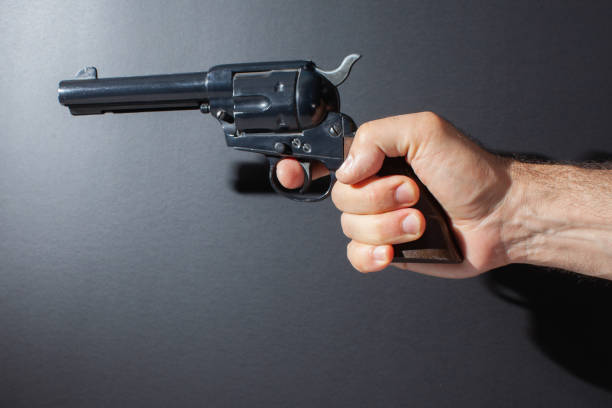 ręczna replika pistoletu izolowana na ciemnym tle - color image cowboy plastic people zdjęcia i obrazy z banku zdjęć