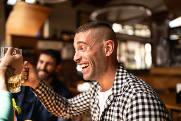 istock Mid adult man talking and drinking a beer at a bar 1412539230