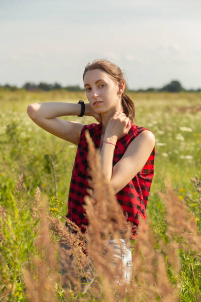 happy young red hair woman in red blouse at sunny meadow looking at camera smiling
