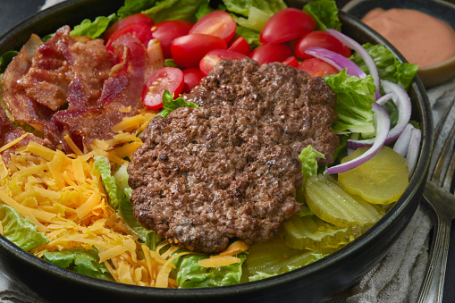 Bacon Double Cheeseburger Salad Bowl with Tomatoes, Lettuce, Red Onions, Pickles and Thousand Island Dressing