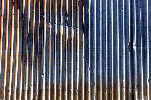 Closeup old, weathered rusty corrugated iron wall in sunlight, abstract background with copy space, full frame horizontal composition