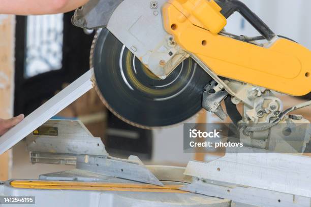 Construction Workers Are Cutting Wood Moldings Baseboards On The Circular Saw For The Finishing Work On The Construction Projects Stock Photo - Download Image Now