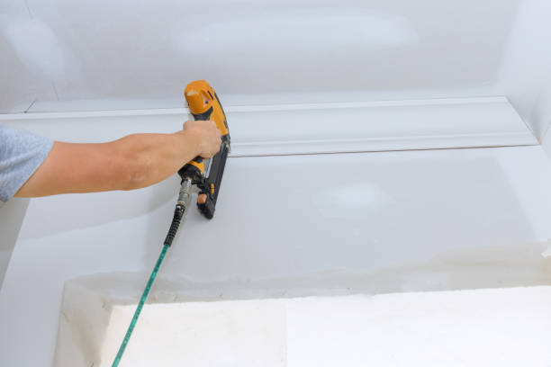 istock Installation of ceiling corner crown molding with carpenter using air nail gun 1412546252