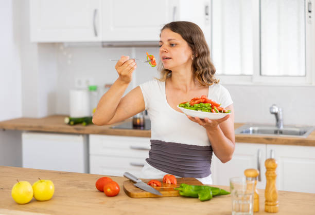 istock Young woman eating vegetable salad in kitchen 1412546641