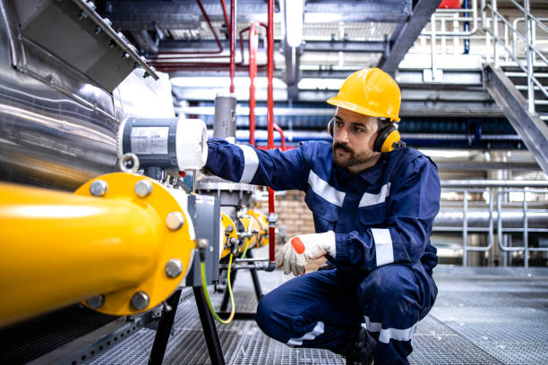 Refinery blue collar worker standing by LPG pipeline and checking gas production or distribution. stock photo