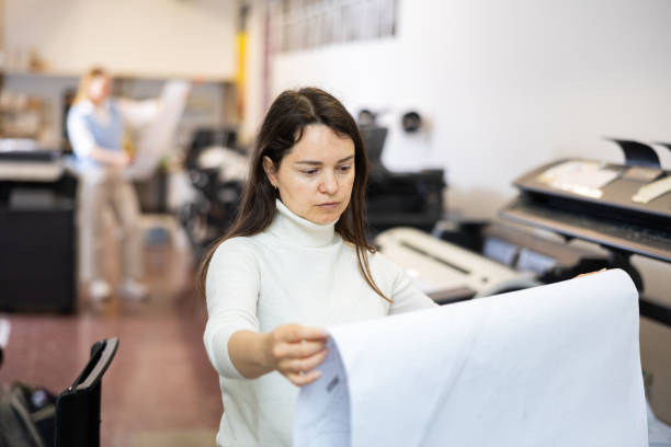 istock Printing establishment worker examining large piece of paper 1412547697