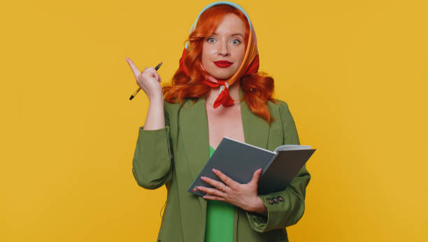 istock Thoughtful journalist redhead woman making notes, writing down thoughts with pen into notebook diary 1412548947