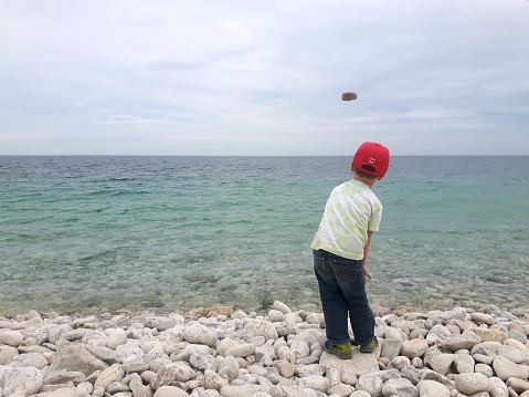 Child On beach throwing stones