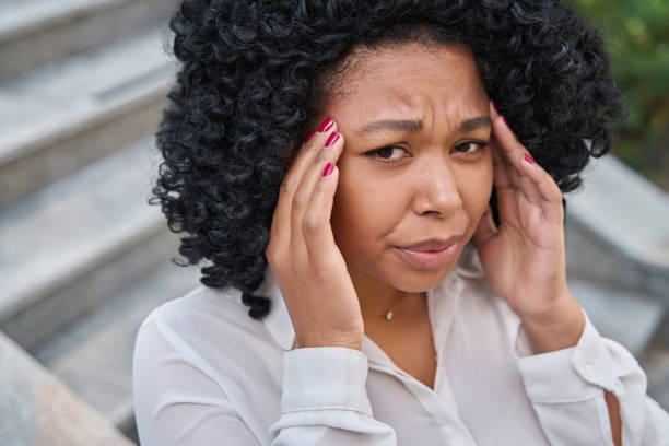 istock Woman clutches her temples and winces in pain 1412552590
