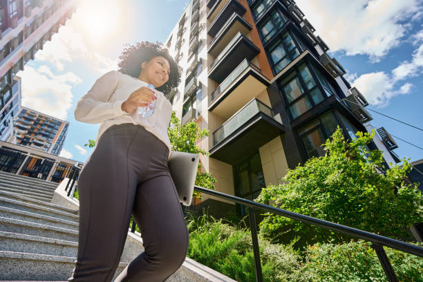 istock Smiling curly woman walking down the stairs 1412552642