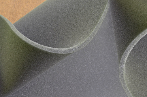 gray foam folding sponge. rubber texture sheet with corrugated edges on brown wooden plank