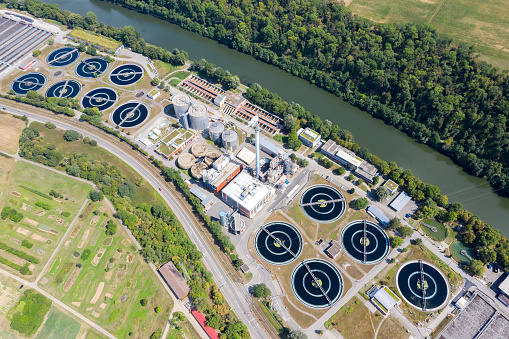 Aerial shot of sewage treatment plant located near a river.