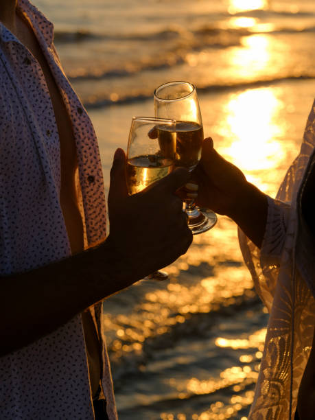 istock honeymoon couple drinking champagne on tropical beach 1412557474