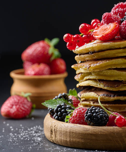 istock A stack of pancakes with fresh fruits poured with syrup on a black background 1412558294