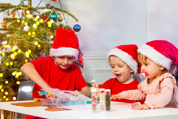 istock Three children prepare gingerbread house with decorations 1412563427