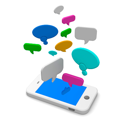 Mobile phone or smartphone lying on the floor with a variety of shapes and sizes of colourful speech bubbles floating in the air above it conceptual of telecommunications and social networking.