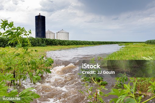 istock Flooding rain water flowing through farm field waterway. Farming, climate change, and erosion control concept. 1412564786