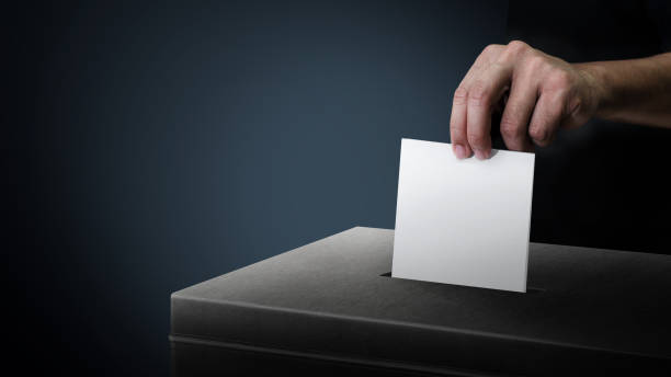 dark side ballot box with hand person vote on blank voting slip at dark background. - vote casting imagens e fotografias de stock